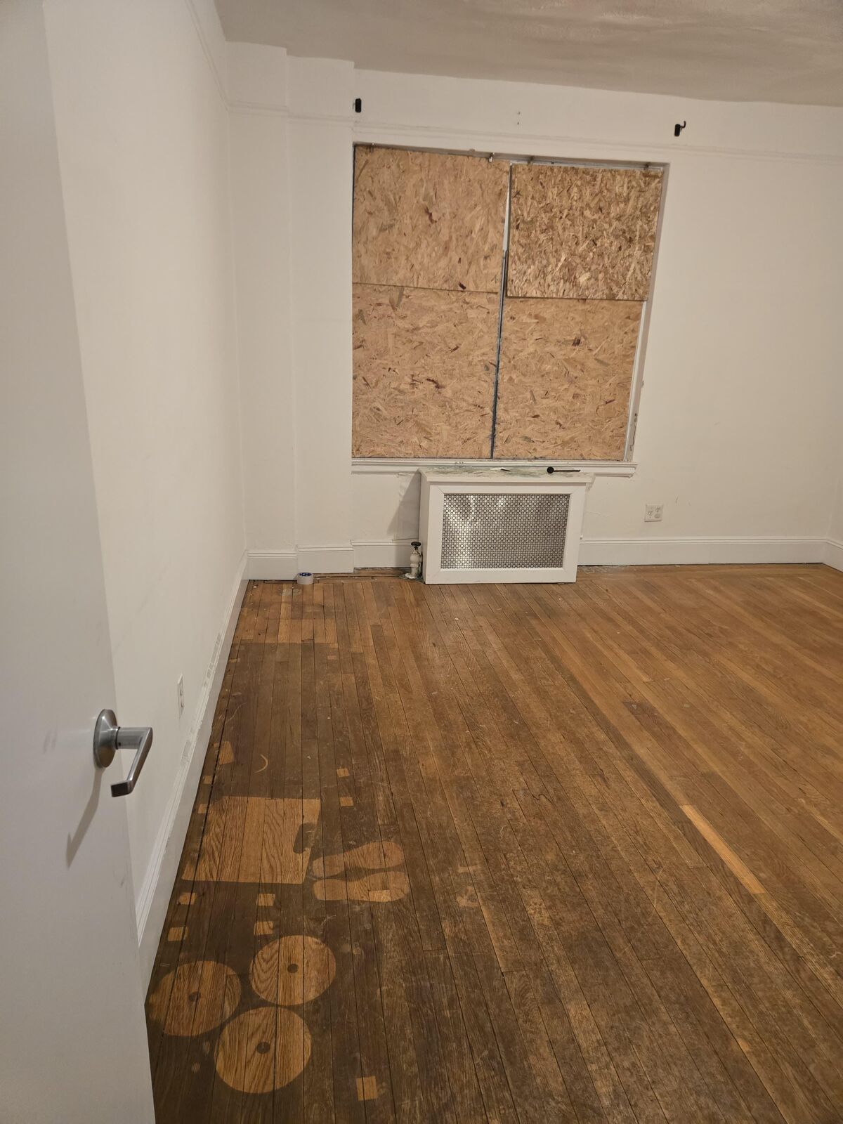 An empty apartment at 75 Pierrepont Street after the fire — boarded-up window, bare floors, everything gone.